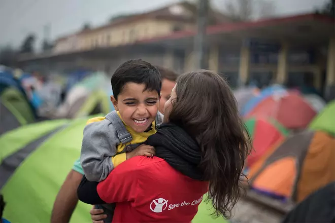 A Save the Children member holds a smiling child in arms