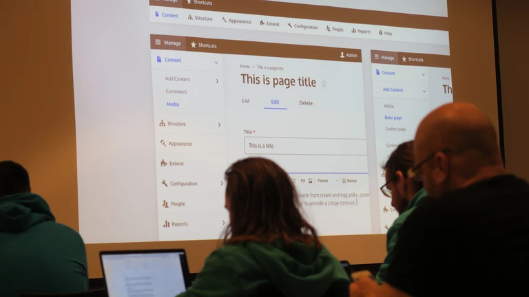 Detalle del público y proyección en una charla de un evento Drupal.